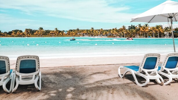 A beachside view with lounge chairs and a clear blue sky.
