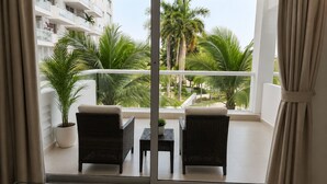A balcony with two wicker chairs, a small table, and a potted plant.