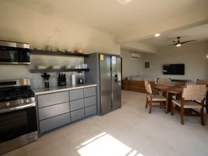Una cocina moderna equipada con refrigerador, estufa, microondas y un comedor con mesa y sillas.