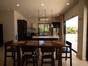 Una cocina moderna con una isla central, luces colgantes y vista a zonas verdes.