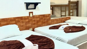 Ein Hotelzimmer mit zwei Betten, einem Holzkopfstück, einer wandmontierten Leuchte und einem sichtbaren Badezimmerbereich.