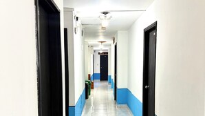 Ein Korridor mit Türen an beiden Seiten, einem Fliesenboden und einer Decke mit Lampen.