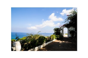 A pathway leading to a white structure with a view of the ocean. - Villa la Prua: A Terrace by the Sea with Pool and Historic Charm (Casamicciola Terme)