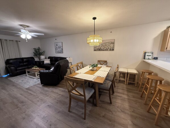 Ein Wohnzimmer mit einer schwarzen Ledersofa, einem Holztisch und einem Essbereich mit Esstisch und Stühlen.