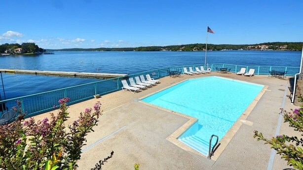Une piscine avec des chaises longues et vue sur un lac.