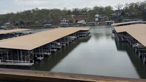 Un port de plaisance avec des bateaux amarrés, une terrasse en bois et une vue sur des maisons en arrière-plan.