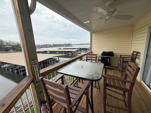 A covered outdoor deck with a table and chairs, a ceiling fan, and a view of a marina. - Waterfront Condo in Osage Beach- 2 pools and beach access. Boat & PWC slip (Osage Beach)