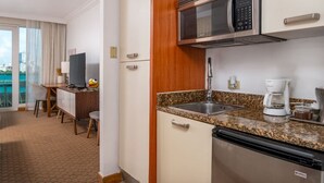 Een kleine hotelkeuken met een magnetron, koffiezetapparaat en een spoelbak.