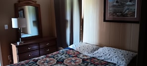 A bedroom with a bed, a dresser, a mirror, and a painting on the wall.