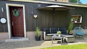 A patio with a dark-colored sofa, a small table, and two potted plants. - Vacation apartment Seelenglück with garden 🪴🦮 (Bad Harzburg)