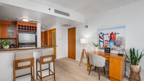 A modern kitchen with a built-in refrigerator, wooden cabinets, and a bar area with two bar stools. - Lagoon Studio · Pool & Hot Tub (San Juan)