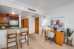 A modern kitchen with a built-in refrigerator, wooden cabinets, and a bar area with two bar stools. - Lagoon Studio · Pool & Hot Tub (San Juan)