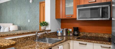 Una cocina con encimeras de granito, electrodomésticos de acero inoxidable, armarios de madera y lavavajillas integrado.