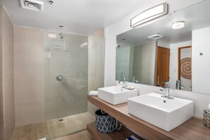A modern bathroom with a glass-enclosed shower, two white sinks, and a large mirror. - Newly Renovated Ocean waterfront Studio - Condado (San Juan)