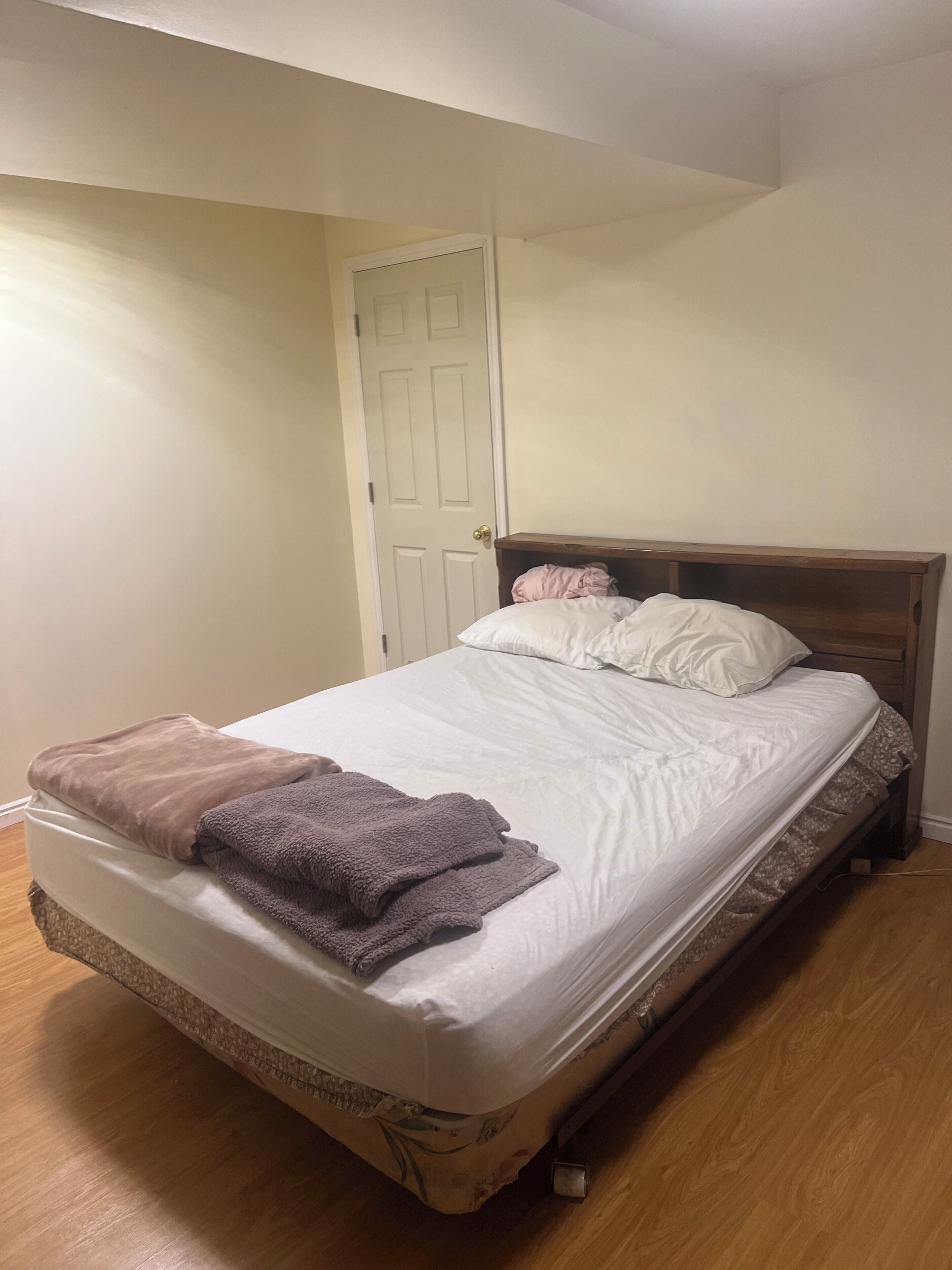 A single bed with a wooden headboard, a brown blanket, and a white pillow.