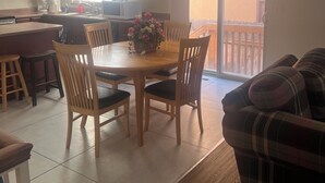 Et køkken med spisebord, stole, sofa og en skydedør til en balkon.