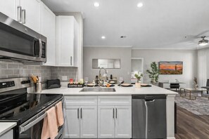 A modern kitchen with a built-in dishwasher, a coffee bar, and a dining area with a table and chairs.