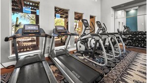 Ein Fitnessraum mit Laufbändern, Crosstrainern und einer Hantelbank.