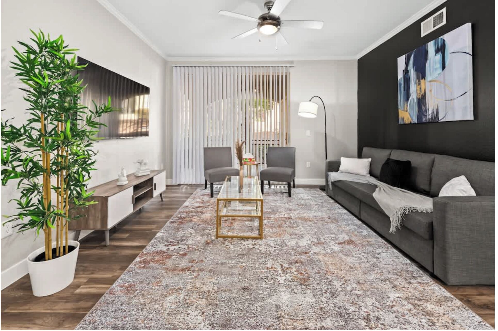Een moderne woonkamer met een bank, stoelen, een salontafel, een vloerlamp en een groot abstract schilderij aan de muur.