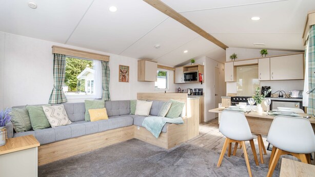 A modern living room with a sofa, dining area, kitchen, and large windows. - Seton Sands 3BR Premium Caravan - Near Edinburgh (Port Seton)
