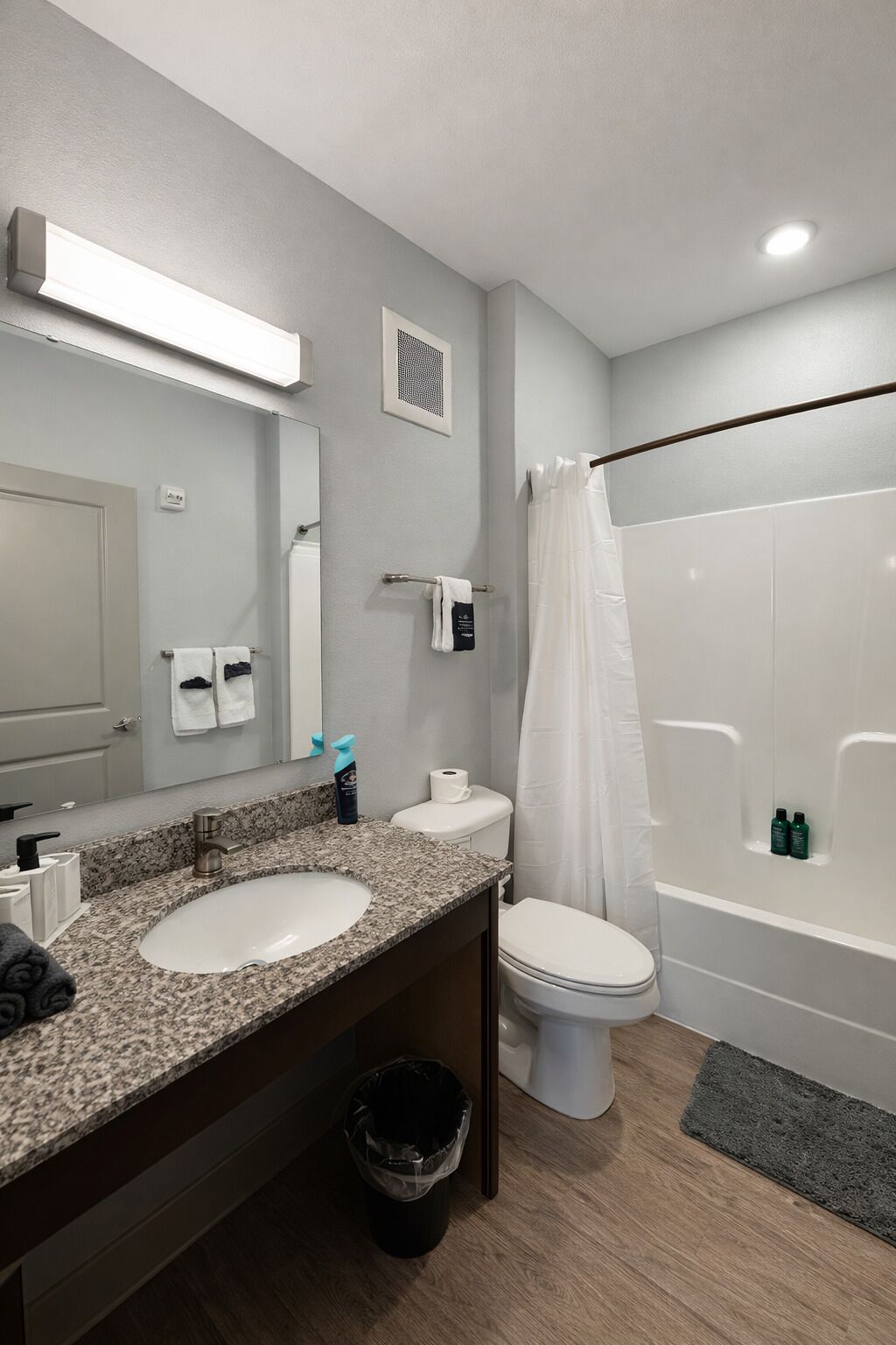 Un bagno con lavabo in granito, wc, vasca da bagno e specchio.