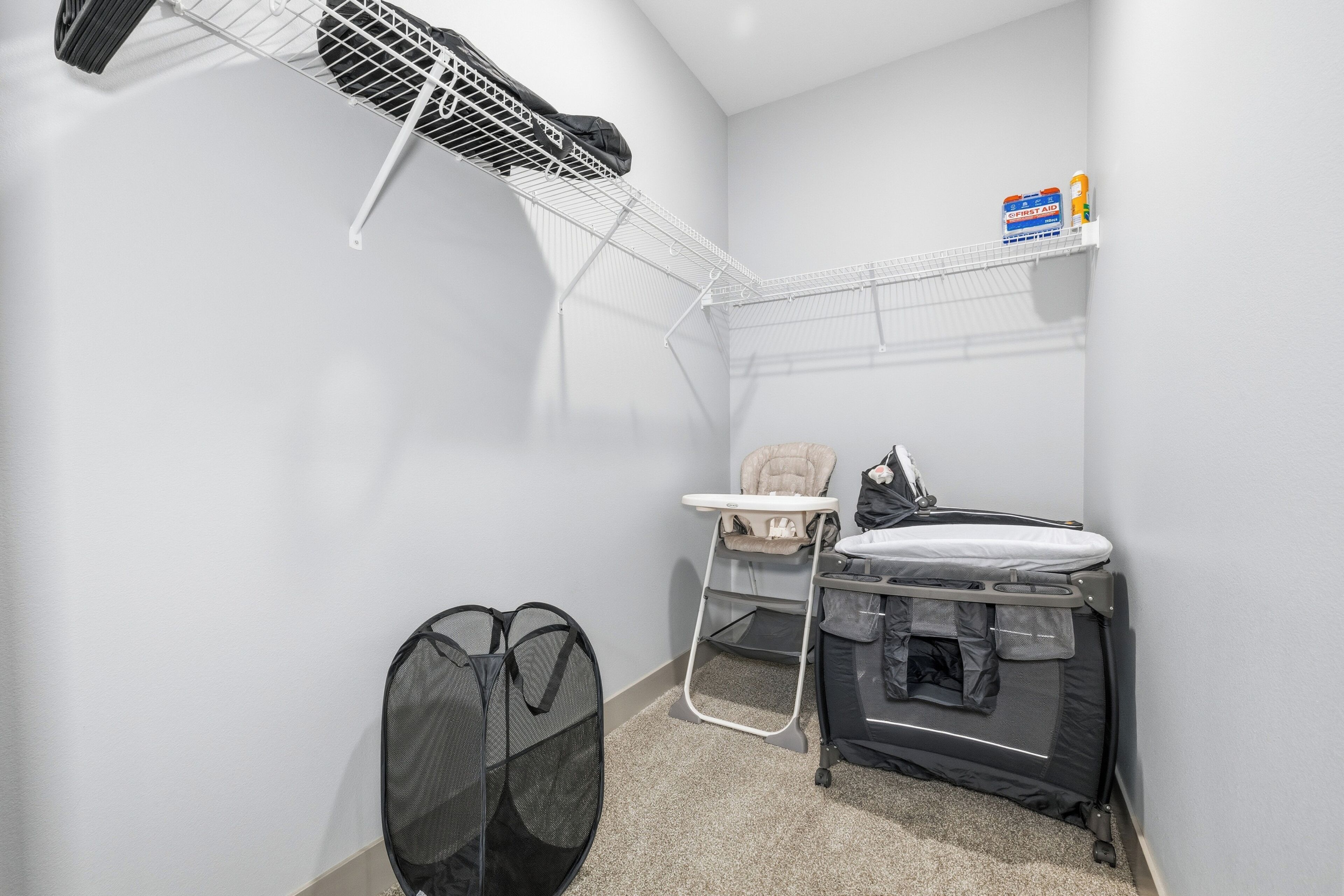 Een compacte kamer met een witte wand, een klein plankje met toiletartikelen, een verschoningsplaats voor baby's, en een zwarte tas.