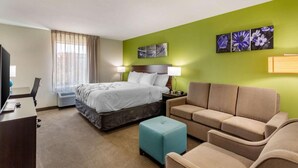 Une chambre d’hôtel comprenant un lit, un bureau, une chaise, un canapé et un téléviseur.