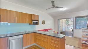 A modern kitchen with wooden cabinets, a microwave, and a ceiling fan.