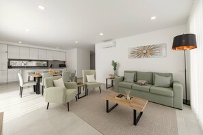 Un salon moderne avec un canapé vert, une table basse en bois et un coin repas comprenant des chaises et une table.