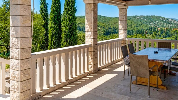 A covered outdoor area with stone pillars, a table with chairs, and a view of green hills. - Amazing home in Zrnovo with WiFi (Zrnovo)