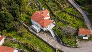 An aerial view of a white building with a red roof, surrounded by terraced gardens and a stone wall. - Amazing home in Zrnovo with WiFi (Zrnovo)