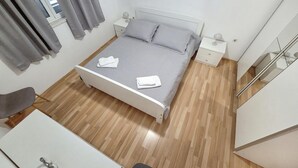 A neatly made bed with pillows and folded towels, a bedside table with a lamp, and a wooden floor. - Amazing home in Zrnovo with WiFi (Zrnovo)