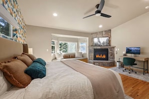 Ein Schlafzimmer mit Bett, Kamin, Schreibtisch und Computer sowie einem Deckenventilator.