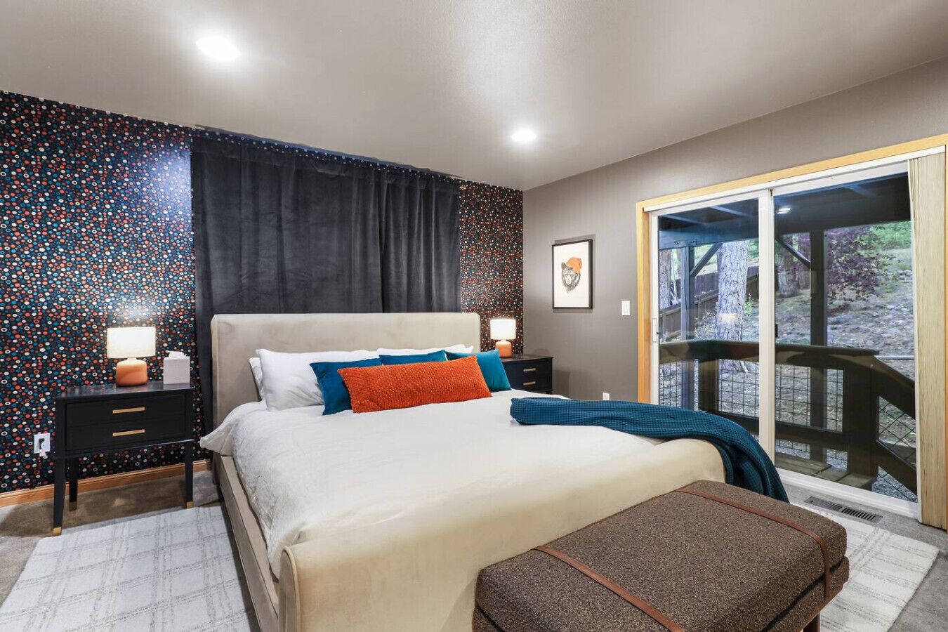 A bedroom with a bed, nightstands, a window, and a view of the outdoors.