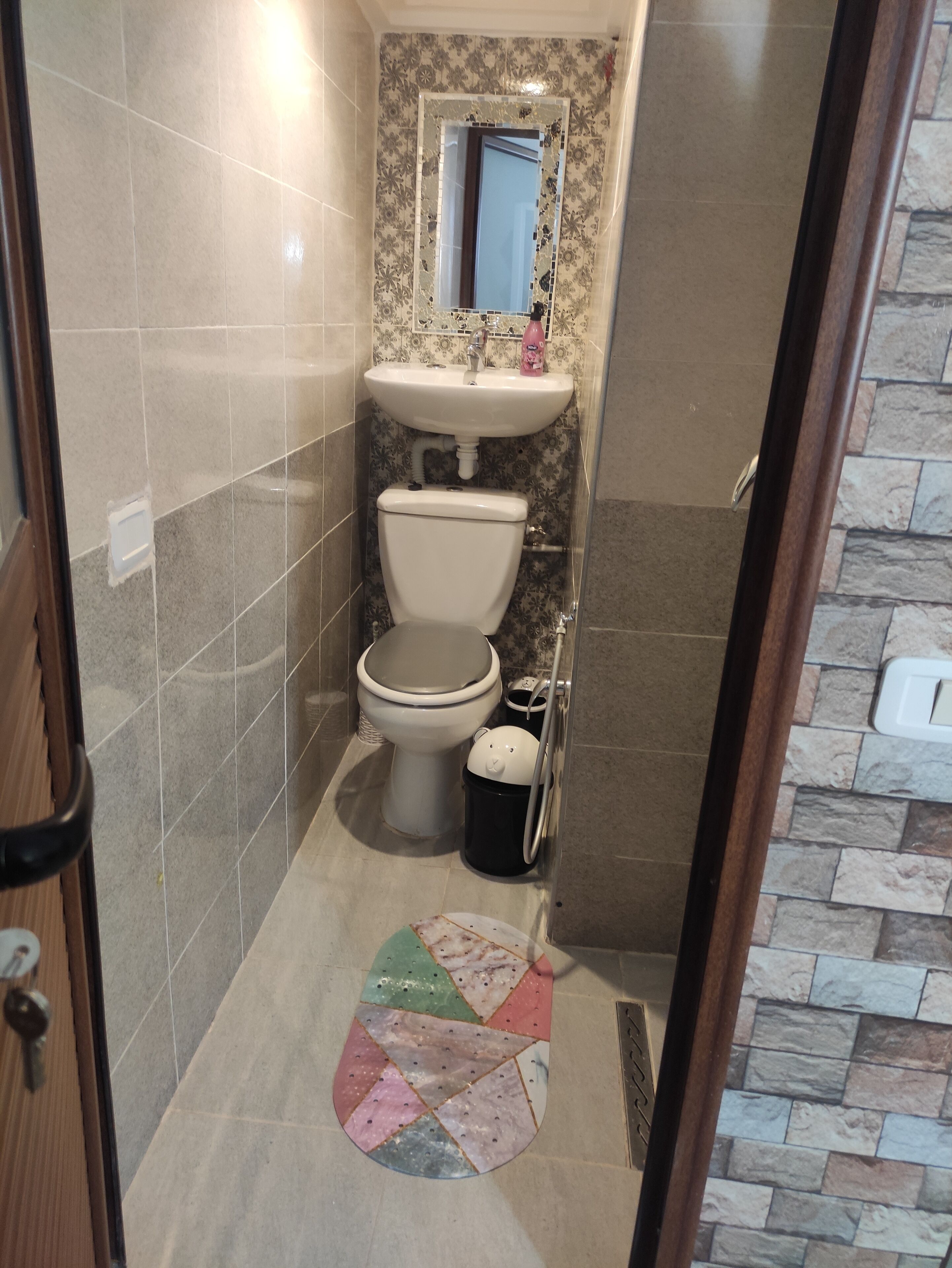 A bathroom with a toilet, sink, and mirror.