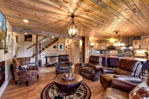 Ein geräumiger Wohnbereich mit Ledersofas, einer Holzbalkendecke und einer Küche im Hintergrund.