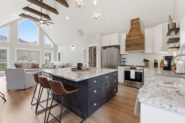A spacious kitchen with a large island, white cabinetry, and a wooden accent wall.