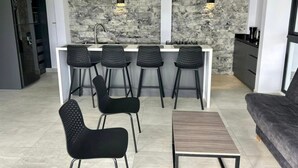 Una cocina moderna con protector de piedra, una isla central con taburetes y un comedor con sillas y mesa.
