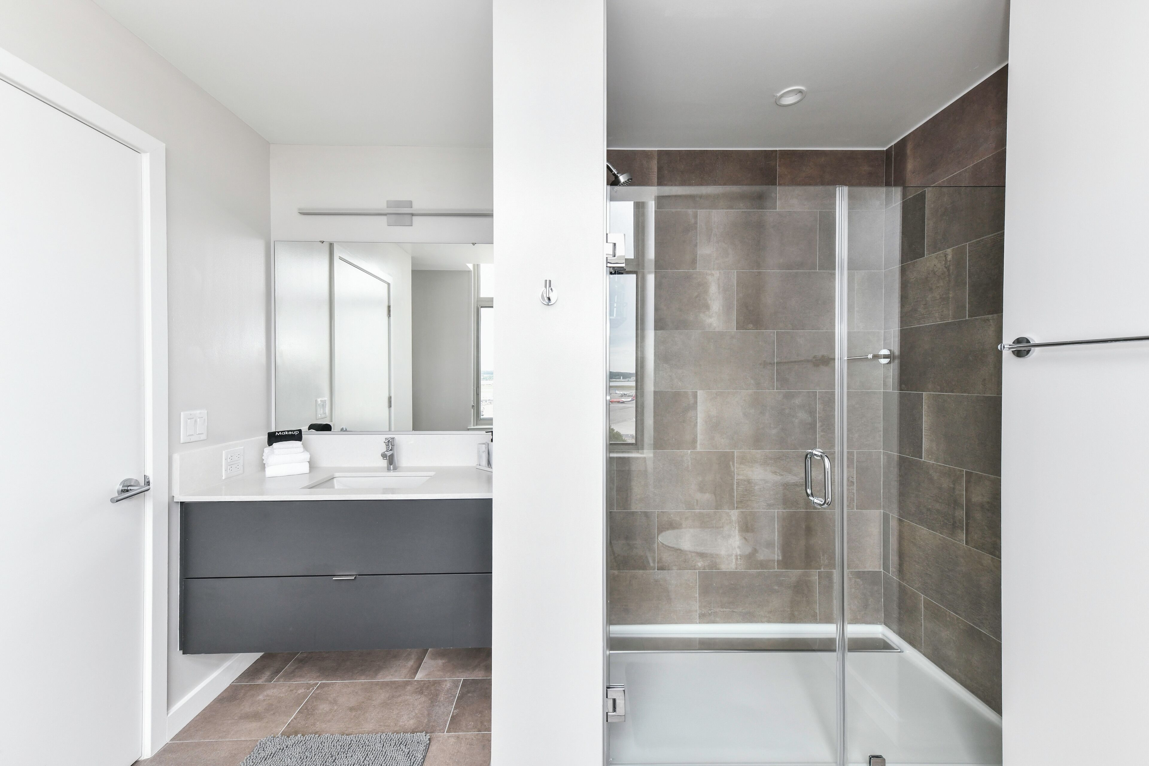 A modern bathroom with a glass shower enclosure, a white sink, and a dark-toned vanity.