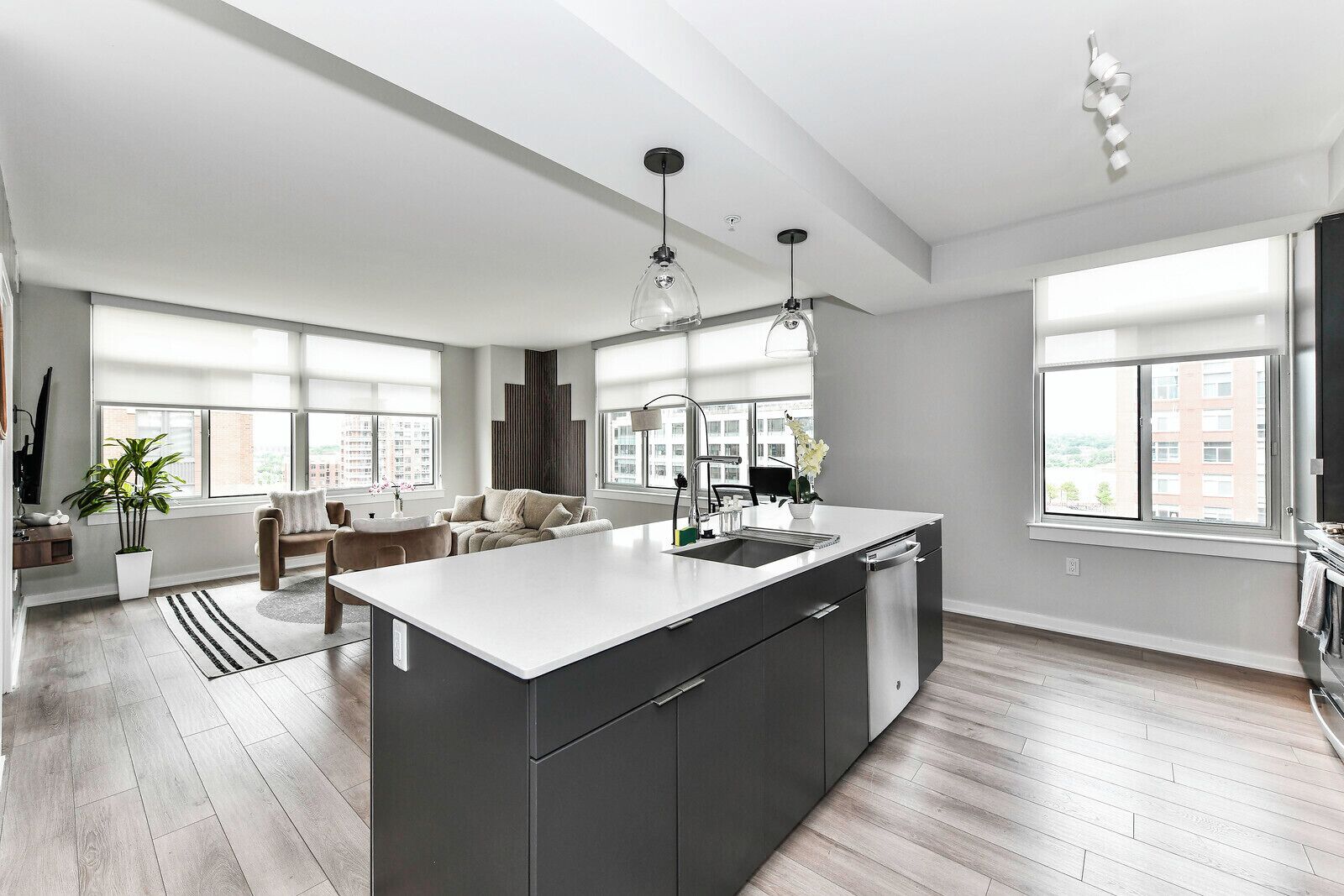 A modern kitchen with a large island, a dining area with a sofa, and large windows providing natural light.