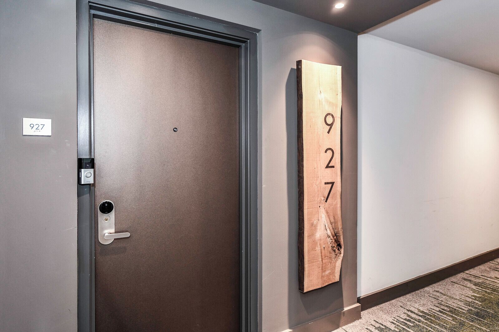 A hotel room with a closed door, a keypad lock, and a wall-mounted number sign.