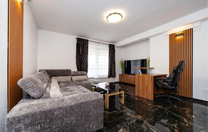Ein modernes Wohnzimmer mit einer Couch, einem Couchtisch, einem Fernseher und einem Schreibtisch mit Stuhl.