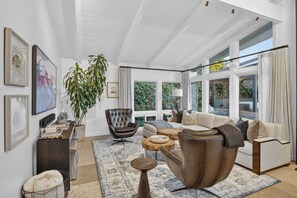 A modern living room with a sofa, armchairs, a coffee table, and a large plant. - La Jolla Luxury | Designer Home w/ Pool & Jacuzzi! (San Diego)