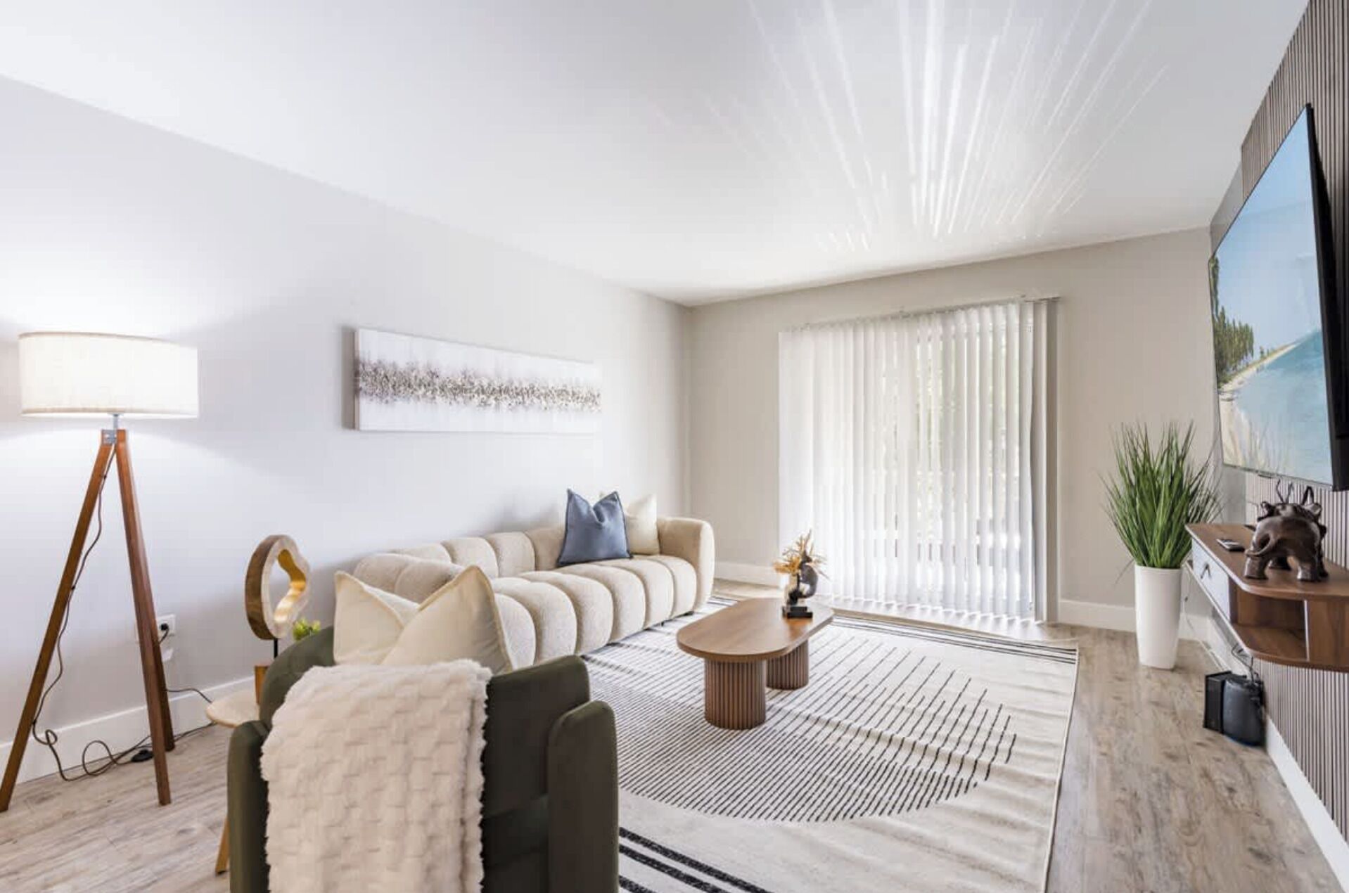Un salon moderne avec un canapé, une table basse, un lampadaire et un tableau accroché au mur.