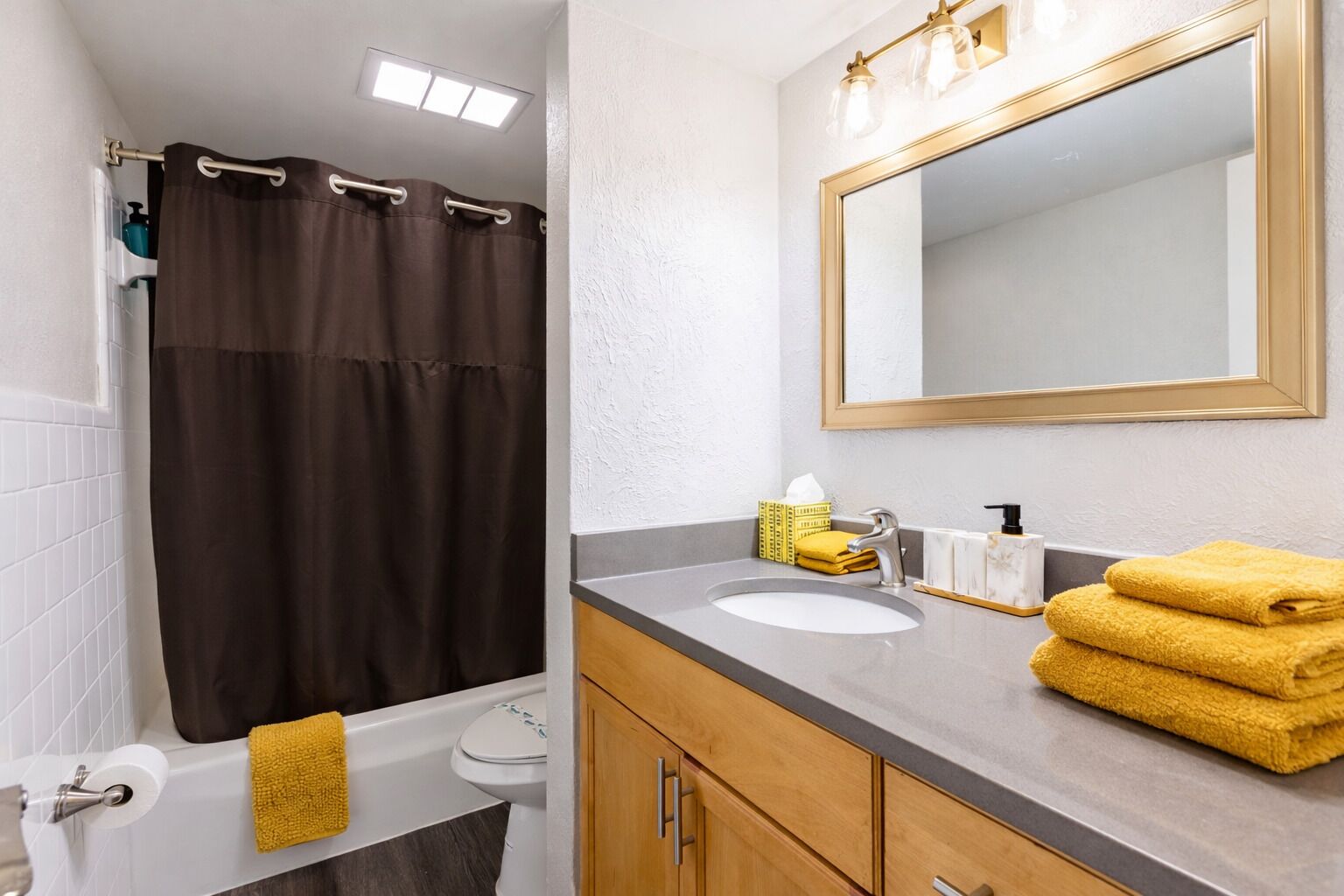 Un baño con bañera, inodoro, lavabo, espejo y toallas.