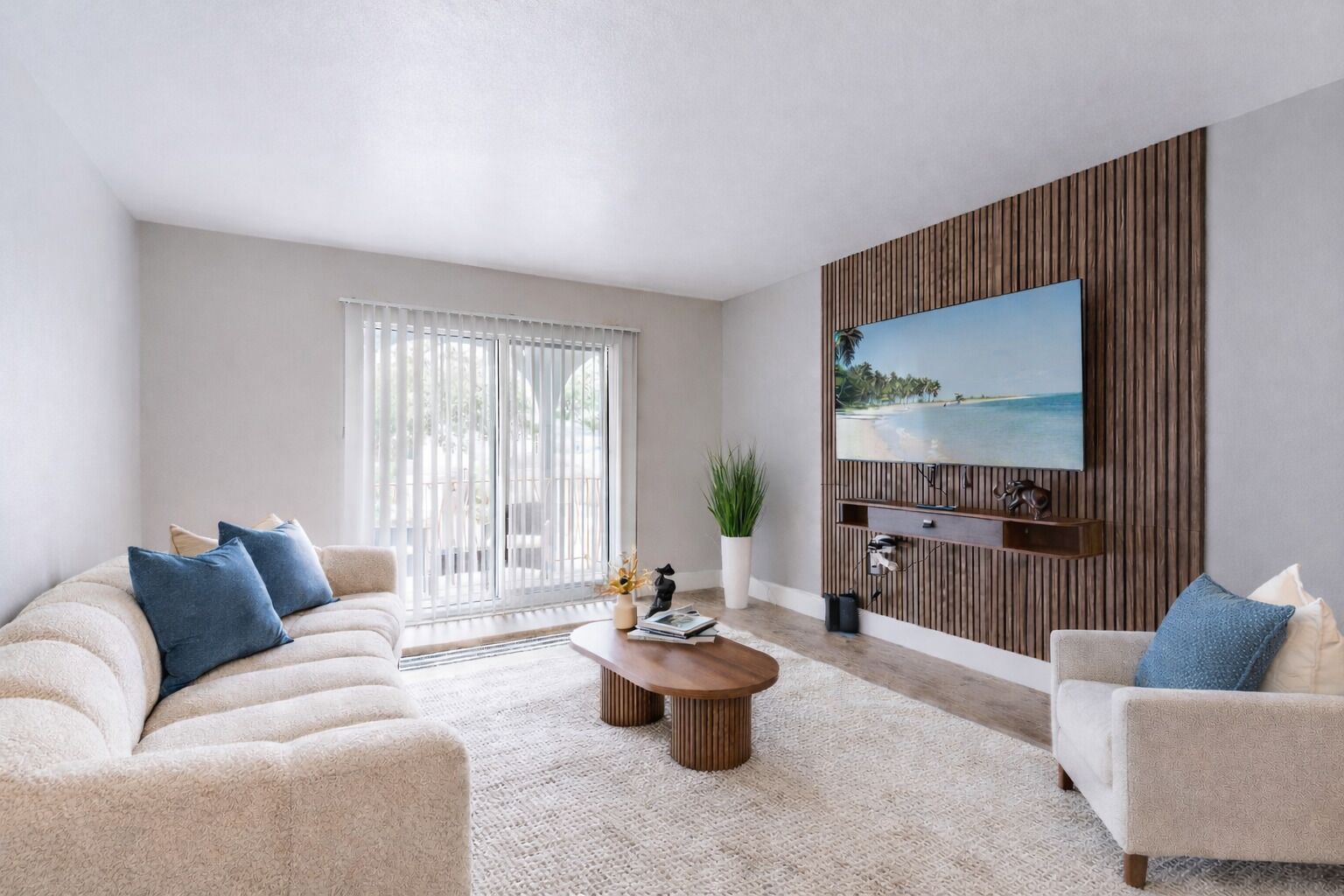 Una sala de estar con un sofá color beige, una mesa de centro y un televisor montado en una pared de madera.