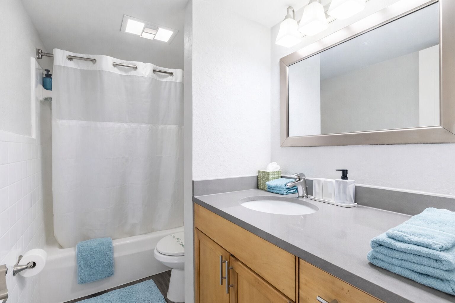 A bathroom with a shower, toilet, sink, and mirror.