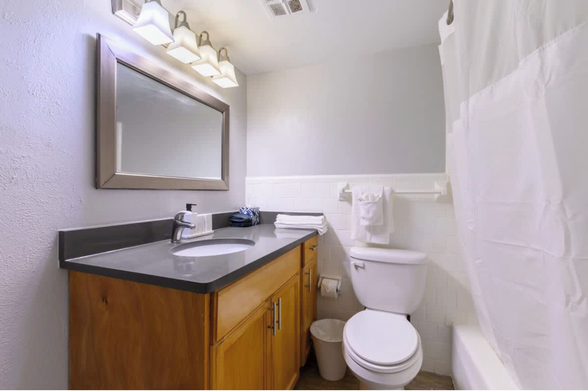 Une salle de bain équipée d’un lavabo, d’un miroir, de toilettes et d’un rideau de douche.