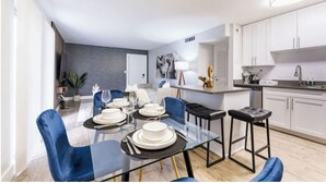 A modern dining area with a glass table, blue chairs, and white plates.