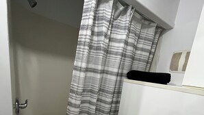 A bathroom with a bathtub, a shower curtain, a towel rack, and a sink. - Charming, cozy studio 7 minutes from Ottawa (Gatineau)